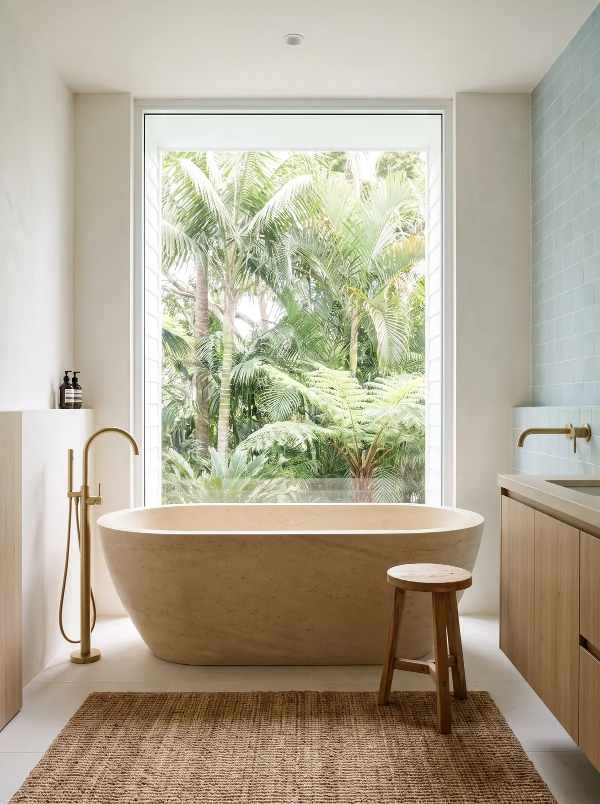 A Byron Bay bathroom with a freestanding stone bath beside a full height window