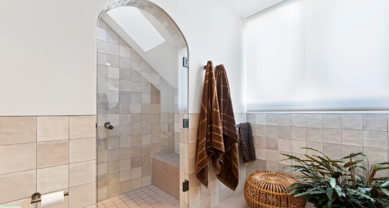An arched shower recess lined in handmade square tile, with a skylight above and a tiled bench seat