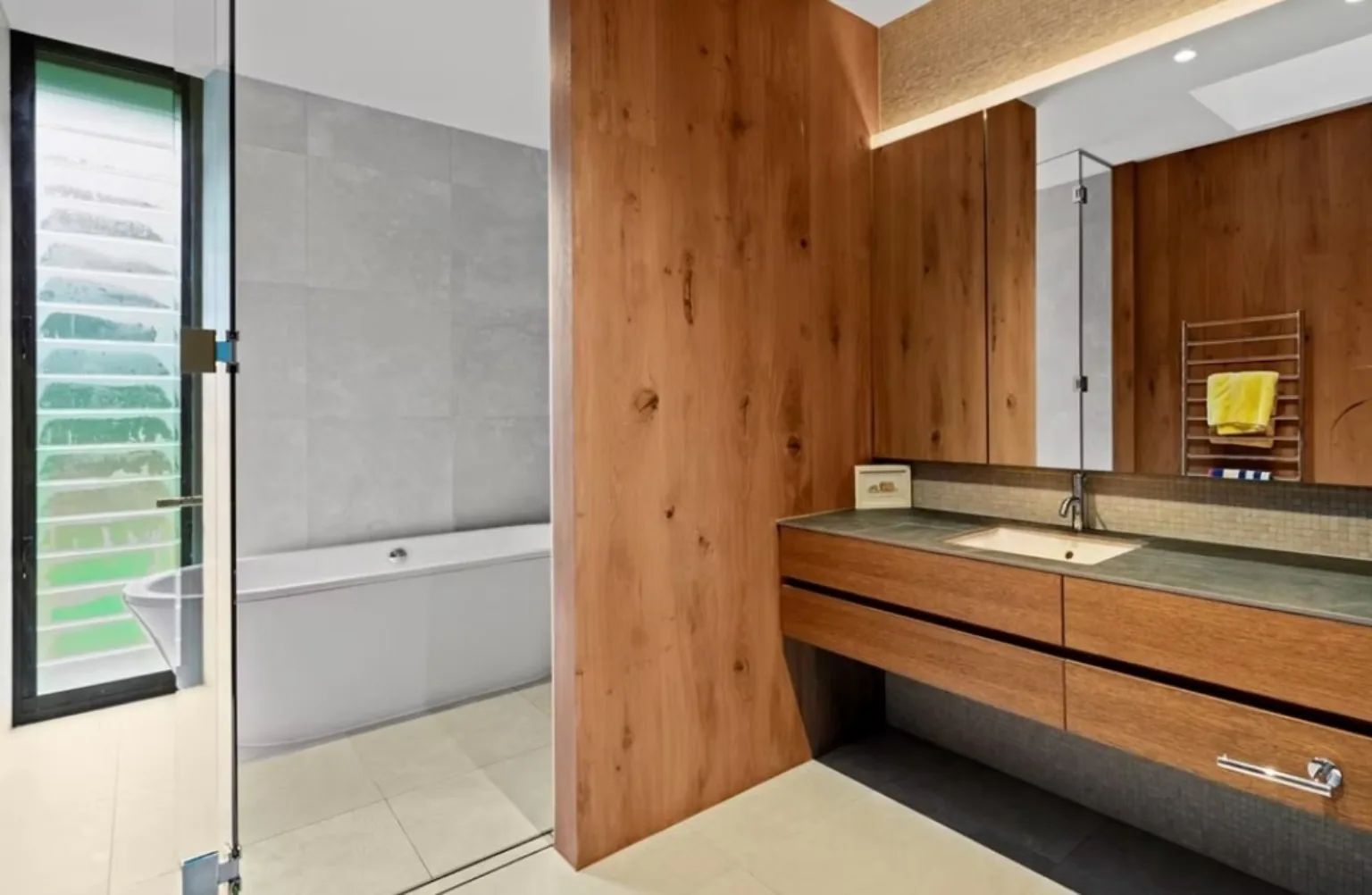 A timber clad wall running behind a floating vanity with a stone top and an undermount basin
